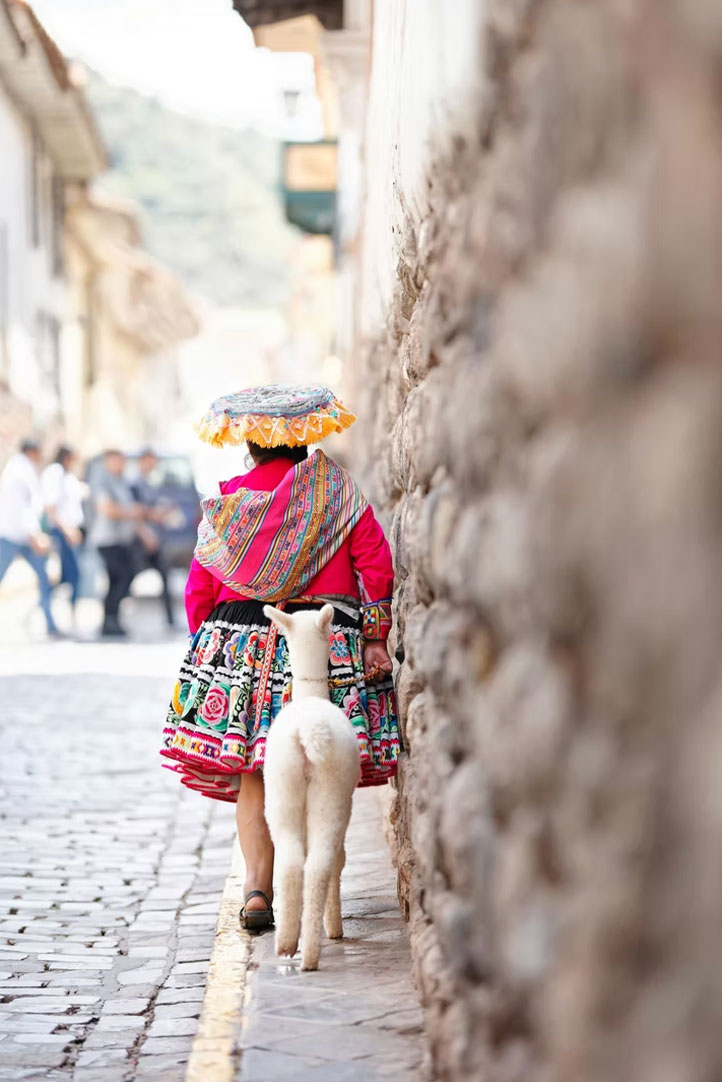 Andean girl walking with an alpaca along a traditional Cusco street
