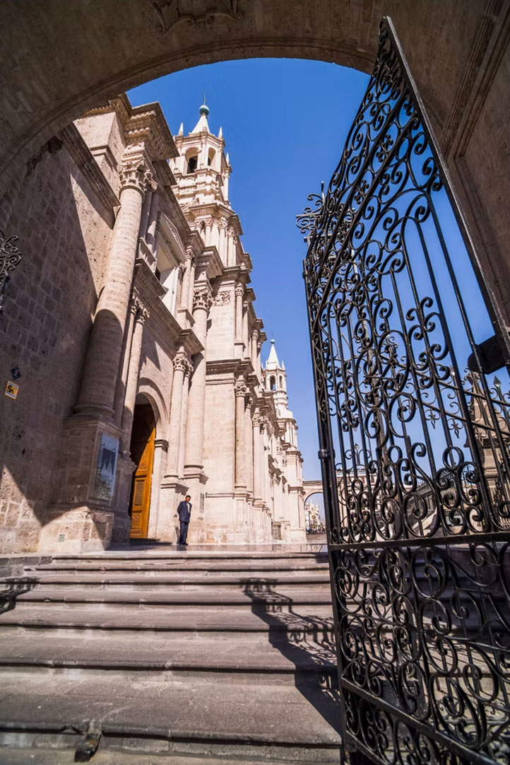 Colonial church architecture in Arequipa seen through an ornate iron gate