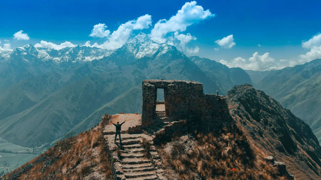 Hiker standing at an ancient stone ruin overlooking the Cusco and Sacred Valley mountains