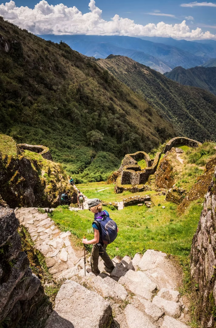 Hiker descending stone steps on the Inca Trail toward Machu Picchu.