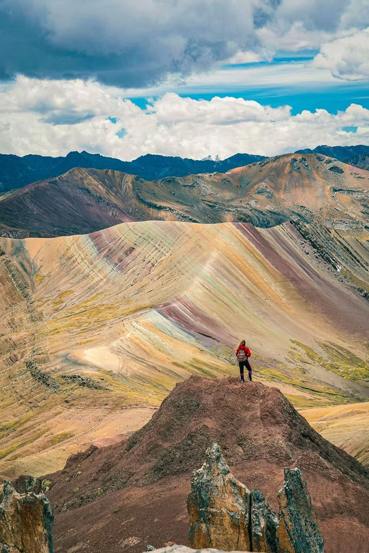 Hiker overlooking the Palcoyo Rainbow Mountains in the Andes of Peru