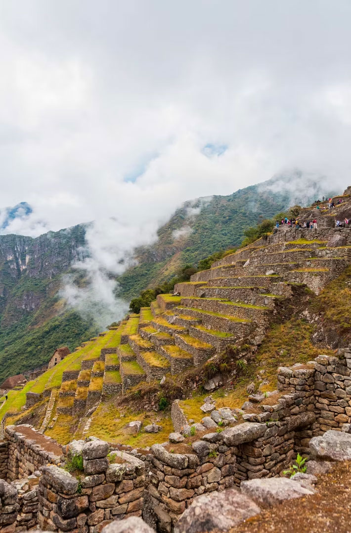 Stone pathway and terraces at Choquequirao ruins with misty mountain backdrop