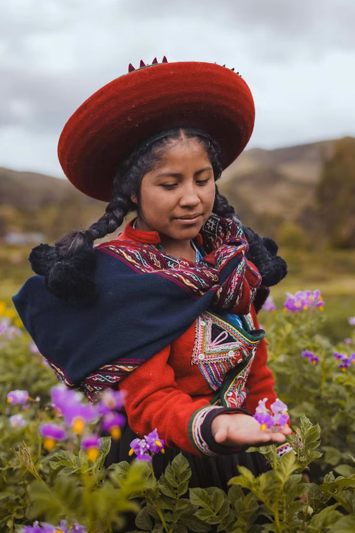Young Andean woman holding wildflowers in a highland landscape