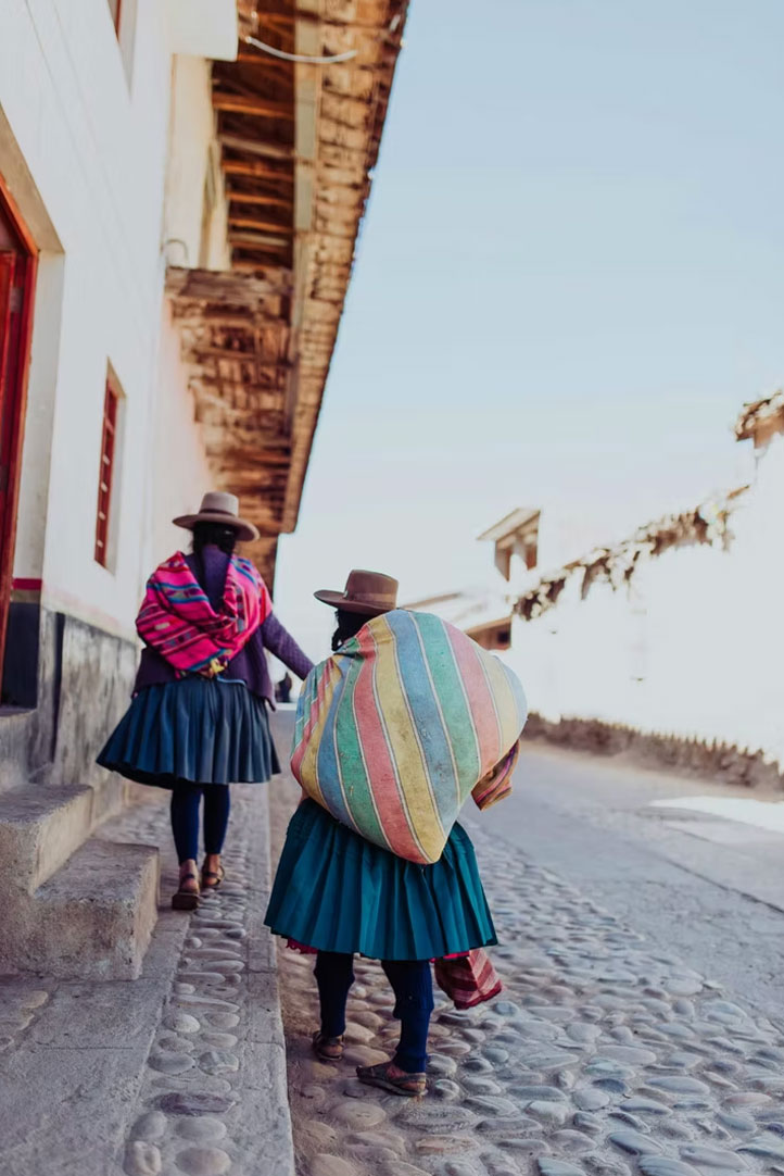 Andean women walking along a cobblestone street in a traditional village