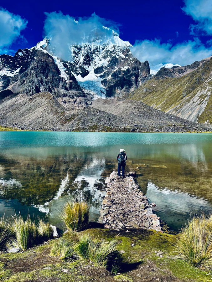 Hiker at a glacial lagoon beneath the Ausangate snow-capped mountain