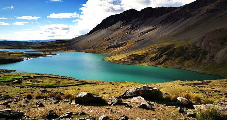 Hiker at a glacial lagoon beneath the Ausangate snow-capped mountain