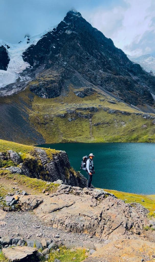 Hiker standing near a high-altitude lagoon during Ausangate trek in Peru